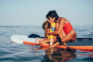 madre con hija en una tabla de paddle foto