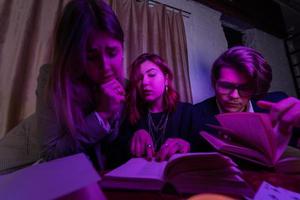 Two women and a guy are reading a mysterious books, close view photo