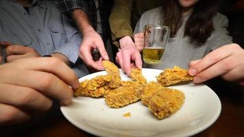 Friends take apart fried legs and wings from a plate in a pub photo