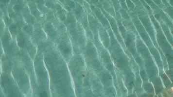 la superficie del agua de la piscina se refleja en un día soleado, el agua clara en el fondo del complejo de vacaciones de verano. video