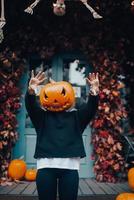 Girl with a pumpkin head scares at the camera photo