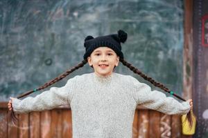 niña en un sombrero posando en el fondo de la pizarra de la escuela foto