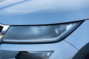 Headlight detail of blue car with water drop after car wash. Close up of headlamp. photo