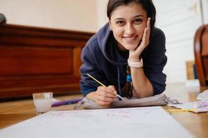 Young woman drawing laying on the floor at home. photo