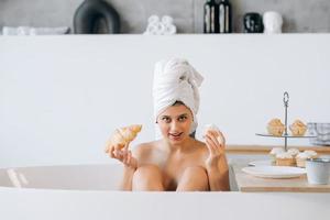 mujer de moda de lujo en la mañana toma el desayuno tumbado en el baño foto