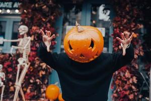 Girl with a pumpkin head scares at the camera photo