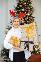 Grandma wearing deer christmas hat. Christmas presents in hands . photo