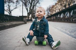 little funny boy with skateboard on the street photo