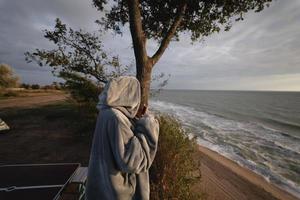 Young woman takes pictures of the sea sunset by smartphone photo