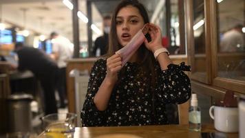 Attractive young woman putting on protective mask in the cafe. photo