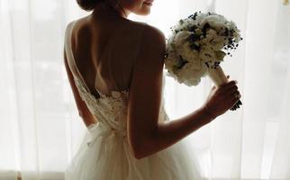 beautiful bride in a wedding dress, by window. photo