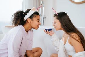 dos chicas en el baño jugando con crema facial foto