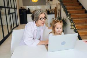 Child and granny looking at the camera with laptop photo