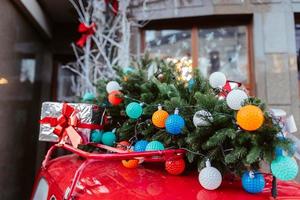 coche retro rojo con un abeto de árbol de navidad atado al techo. foto