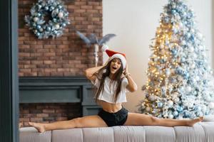 Young beautiful woman practicing split near the christmas tree photo