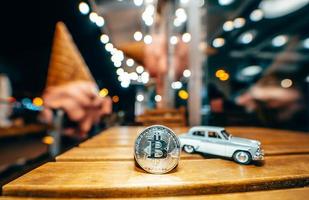 Silver bitcoin and Moskvich 401 on the table, glowing background photo