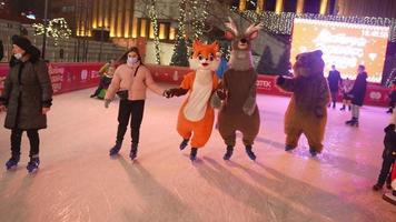 la gente disfruta del patinaje sobre hielo en la calle alrededor del árbol de navidad en la pista. foto