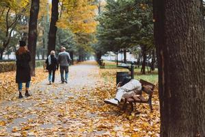 Homeless sleeping on the benches in the autumn park photo