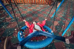 Happy child girl on swing. Little kid playing in the autumn pack. photo