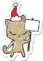 cute distressed sticker cartoon of a cat with sign wearing santa hat vector