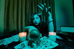 Woman fortune-teller guesses fate of night at table with candles photo