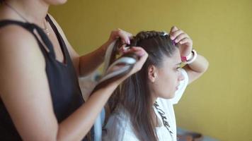 Process of braiding. Master weaves braids on head in a beauty salon, close up photo