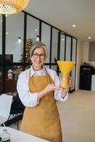 Happy senior woman showing pasta on camera. photo