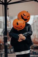 un chico y una chica con cabezas de calabaza posando en la calle foto