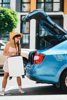 Woman packing her suitcase into luggage boot of the car. photo