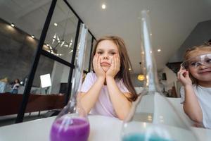 Little girls making chemical experiments at home photo