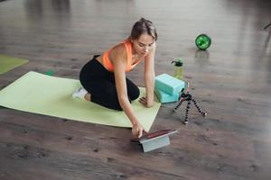 Young woman practicing yoga, is engaged with the teacher online. photo