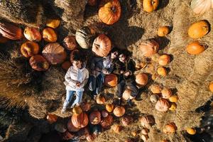 Young girls lie on haystacks among pumpkins. View from above photo