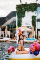 mujer en flotador inflable de colchón de juguete de unicornio en la piscina. foto