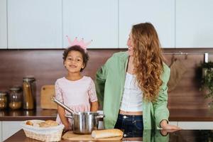 feliz mamá y su hija se divierten mientras cocinan en la cocina. foto