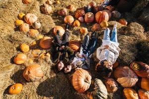 Young girls lie on haystacks among pumpkins. View from above photo