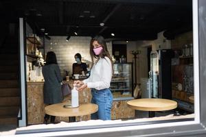 Woman using sanitizer gel cleans hands of coronavirus virus at cafe. photo