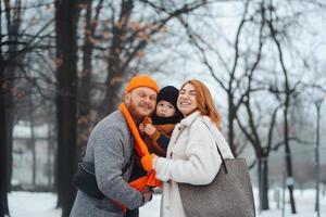papá mamá y bebé en el parque en invierno foto