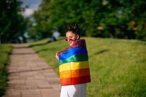 Young woman with lgbt pride flag walking in the park. photo