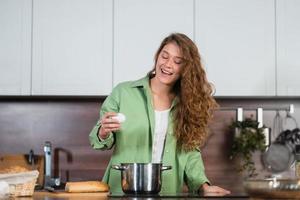 Young woman is preparing food in the kitchen. Beating eggs. photo