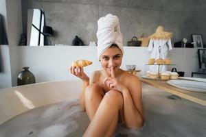 mujer de moda de lujo en la mañana toma el desayuno tumbado en el baño foto