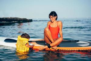 madre con hija en una tabla de paddle foto