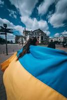 Young woman carries the flag of Ukraine fluttering behind her photo