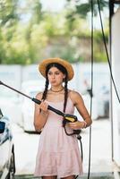 Woman with high pressure hose at car wash photo