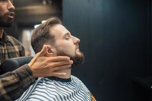 aplicación de loción facial para después del afeitado en la peluquería. foto