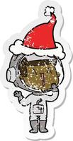 laughing distressed sticker cartoon of a astronaut wearing santa hat vector