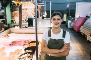 Female fishmonger standing near seafood shop counter photo