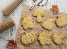 Cookies shaped like pumpkin and leaves on rustic wood background photo