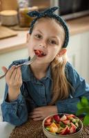 linda niña come ensalada de frutas foto