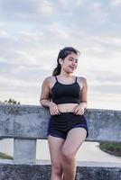 mujer asiática relajándose en un puente después de trotar al atardecer. foto