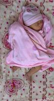 Newborn baby girl having a nap in co-sleeper crib attached to parents' bed photo